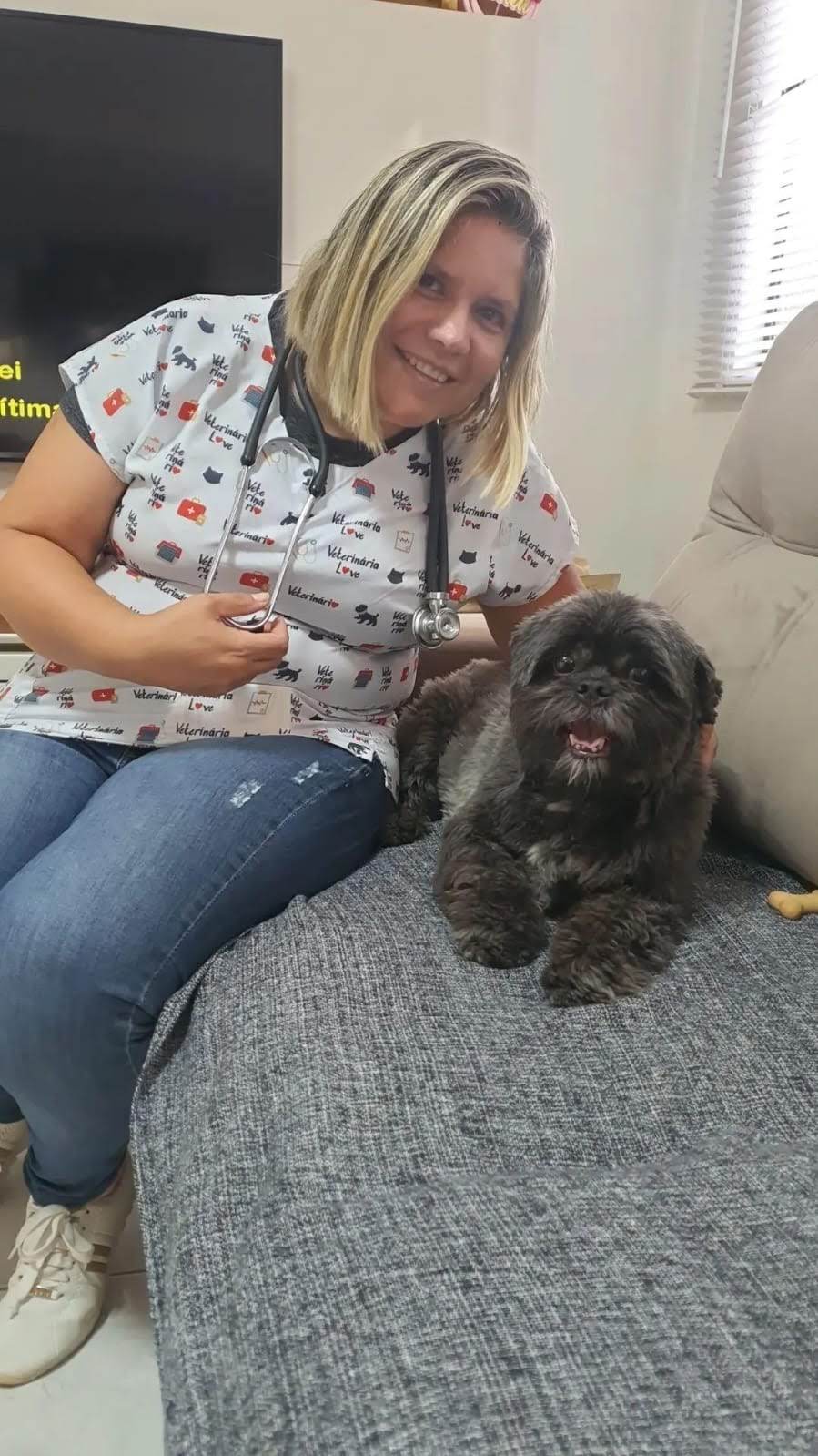 Dra. Quesia Klaus examinando um cão no sofá da casa do tutor