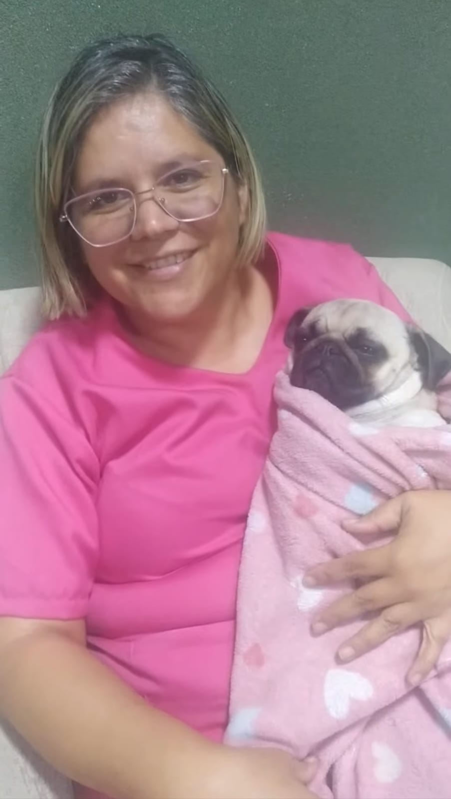 Dra. Quesia Klaus acolhendo um pug enrolado em manta